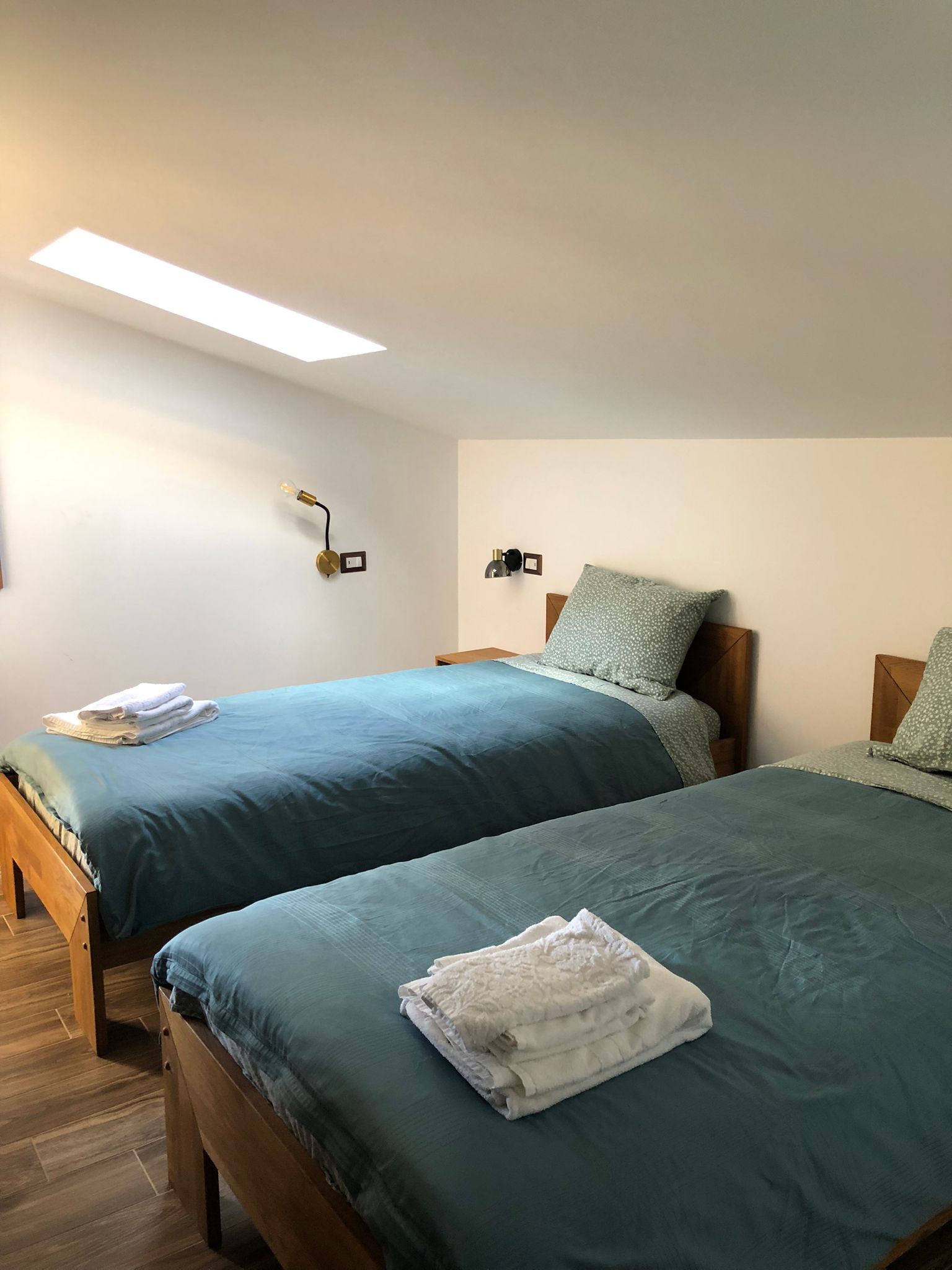 foto da un altra angolazione della camera da letto su una mansarda con due lettini e pavimento in legno